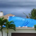 Roof with blue tarp indicating a leak.